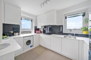 Una cocina blanca con lavadora y secadora. en Relax, Play and Work in London, en Londres