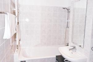 ein weißes Badezimmer mit einem Waschbecken und einer Badewanne in der Unterkunft Great central premium 1 BR apartment in best area 10117 Berlin Mitte, Leipziger Straße in Berlin
