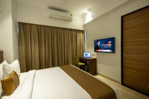 a hotel room with a bed and a flat screen tv at Freesia Residency By Express Inn - Navi Mumbai in Navi Mumbai