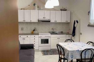a kitchen with white cabinets and a table with chairs at Appartamento centrale a Soverato in Soverato Marina