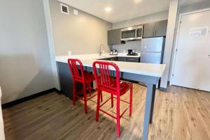 una cocina con 2 sillas rojas y una encimera blanca en Hawthorn Extended Stay by Wyndham Ellsworth Bar Harbor en Ellsworth