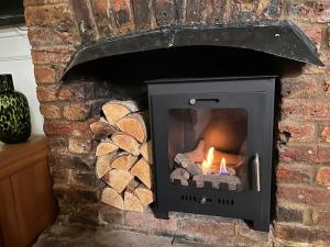 una chimenea de piedra con fuego en Contented Cottage - 2 Bedrooms, Zone 5, en Buckhurst Hill