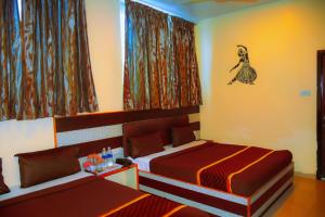 a bedroom with two beds and a woman on the wall at Madurai Grands Inn in Madurai