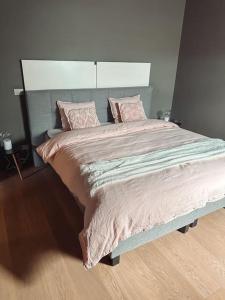 a bedroom with a large bed with pink sheets and pillows at Loft @ de Vlaamse Ardennen in Brakel