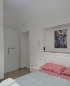 a white bedroom with a bed and a painting on the wall at Suite Europa in San Vito dei Normanni