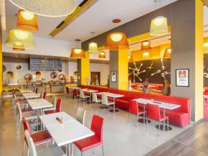 a restaurant with white tables and red chairs at ibis Nashik - An Accor Brand in Nashik