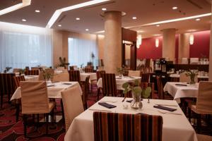 uma sala de jantar com mesas e cadeiras brancas em DoubleTree by Hilton Bratislava em Bratislava