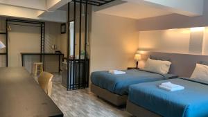 ein Hotelzimmer mit 2 Betten und einem Tisch in der Unterkunft Jeboutiquelangsuan hotel in Lang Suan