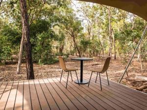 einen Tisch und zwei Stühle auf einer Holzterrasse in der Unterkunft Cooinda Lodge Kakadu in Jabiru