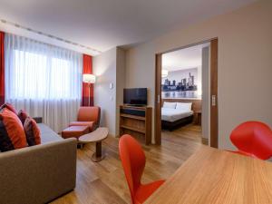 uma sala de estar com um sofá, uma cama e uma televisão em Aparthotel Adagio Frankfurt City Messe em Frankfurt