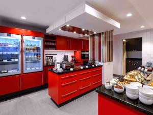 a kitchen with red cabinets and a counter with food at Aparthotel Adagio Frankfurt City Messe in Frankfurt/Main