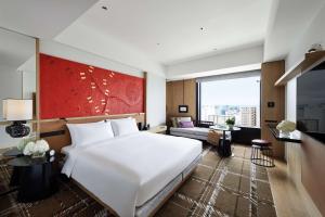 a bedroom with a large white bed and a living room at Hyatt Centric Kanazawa in Kanazawa