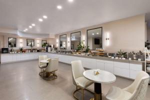 a large kitchen with white counters and tables and chairs at Wyndham DFW Airport in Irving