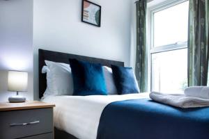 a bed with blue and white pillows and a window at Cosy 3-Bedroom Willow House in Selby