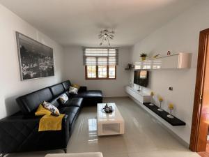 uma sala de estar com um sofá de couro preto e uma mesa em El rincón de Cornelia en Tejeda em Tejeda