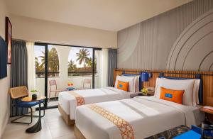 a hotel room with two beds and a balcony at Ronil Goa - a JdV by Hyatt Hotel in Calangute