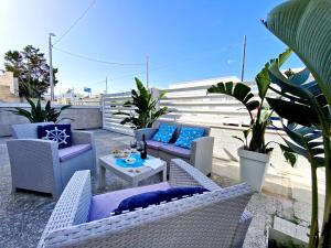 un patio con sillas de mimbre y una mesa con almohadas azules en Aria di Mare - Elegante appartamento con patio, en Marina di Mancaversa