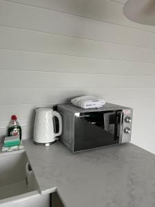 un microondas en la parte superior de una barra de cocina en The Pod @ Cold Comfort Farm en Hinckley