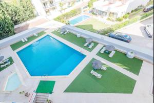 阿爾布費拉的住宿－Apartamento em Albufeira - Condomínio com Piscina，享有带桌椅的游泳池的顶部景致