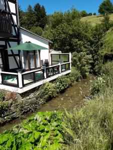 ein Haus mit einem Regenschirm neben einem Fluss in der Unterkunft Elpe in Olsberg