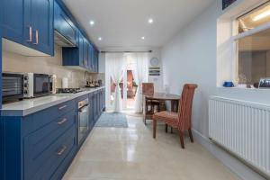 una cocina con armarios azules y una mesa. en Stunning 3-Bed House, en Londres