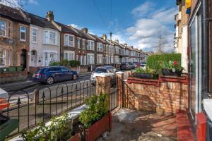 una calle con casas y coches estacionados en la calle en Stunning 3-Bed House, en Londres