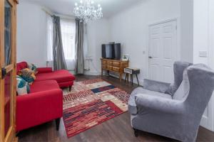 salon z czerwoną kanapą i 2 krzesłami w obiekcie Stunning 3-Bed House w Londynie