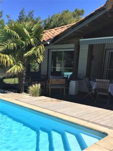 uma piscina ao lado de uma casa com uma palmeira em Villa piscine privée chauffée,vélos fournis, plage em Moliets-et-Maa