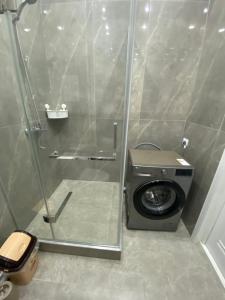 a shower stall with a washing machine in a bathroom at Однокомнатные бизнес апартаменты в ЖК Заман in Atyraū
