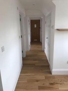 a hallway with white walls and a wooden floor at Luxury Penthouse Appartment in Cobham