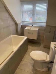 a bathroom with a toilet and a tub and a sink at Luxury Penthouse Appartment in Cobham