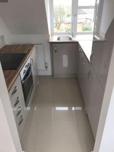 uma pequena cozinha branca com um lavatório e uma janela em Luxury Penthouse Appartment em Cobham