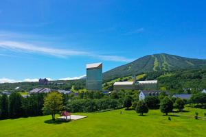 un campo verde con un edificio sullo sfondo di ANA Crowne Plaza Resort Appi Kogen, an IHG Hotel a Hachimantai