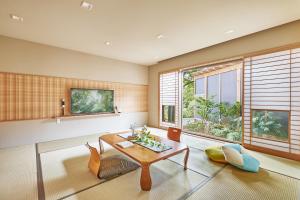 a living room with a table and chairs and windows at Arima Onsen Motoyu Ryuusenkaku in Kobe