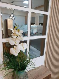 un vaso con fiori bianchi davanti a uno specchio di Lux Apartment Dolce Casa Skopje Karpos IV a Dolno Nerezi