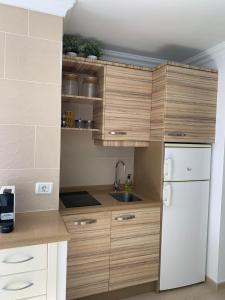 a kitchen with wooden cabinets and a white refrigerator at Sol y Sea Holiday Homes Don Paco in Patalavaca