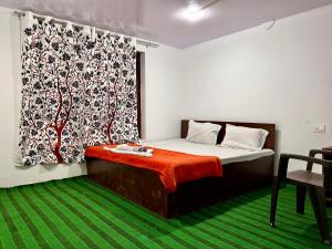 a small bedroom with a bed with a red blanket at Hotel Border View in Kargil