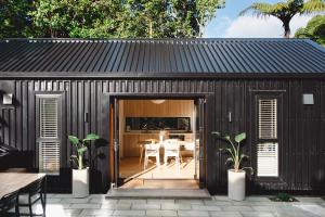 a black shed with a dining room and a table at Urban oasis with sauna in Wellington