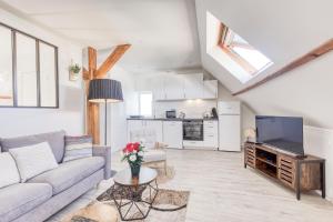 a living room with a couch and a tv at Le Boisier - 3 min de la Gare Massy TGV - Cozy Houses in Palaiseau
