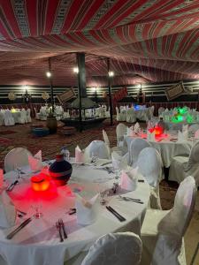 um quarto com mesas brancas e cadeiras brancas e uma mesa de trabalho em Rum Oasis Luxury Camp em Wadi Rum