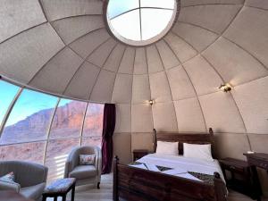 a bedroom in a dome with a bed and a window at Rum Oasis Luxury Camp in Wadi Rum