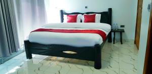 a bed with red pillows on it in a room at Kivu Summer Hotel in Rubavu