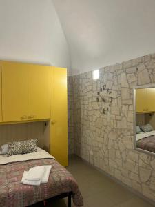 een slaapkamer met een stenen muur, een bed en een spiegel bij Monolocale Elena in Vieste