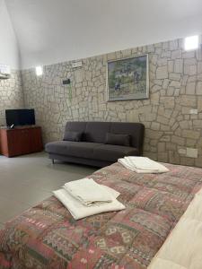 een slaapkamer met een bank en een bed met handdoeken erop bij Monolocale Elena in Vieste