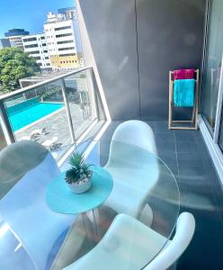 a balcony with a table and chairs and a pool at AQUA 306 POOLSIDE Luxury Apartment , Honeysuckle, NEWCASTLE FREE Parking in Newcastle