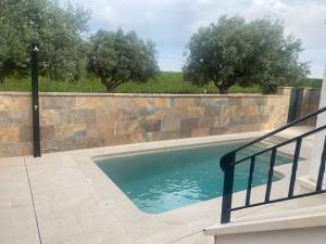 a swimming pool next to a stone wall with trees at Villa Jacaranda in Torre-Pacheco