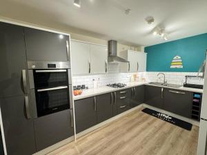 a kitchen with gray appliances and a wooden floor at Beautiful Home in Wolverhampton! in Wolverhampton