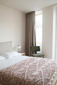 - une chambre avec un lit, une chaise et une fenêtre dans l'établissement Corujeira Apartments, à Porto