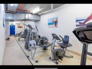 - une salle de sport avec plusieurs tapis de course et appareils de cardio-training dans l'établissement Amazing Water View Apartment - Pool, Gym, Parking., à Urangan
