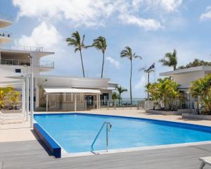une piscine en face d'un bâtiment avec des palmiers dans l'établissement Amazing Water View Apartment - Pool, Gym, Parking., à Urangan